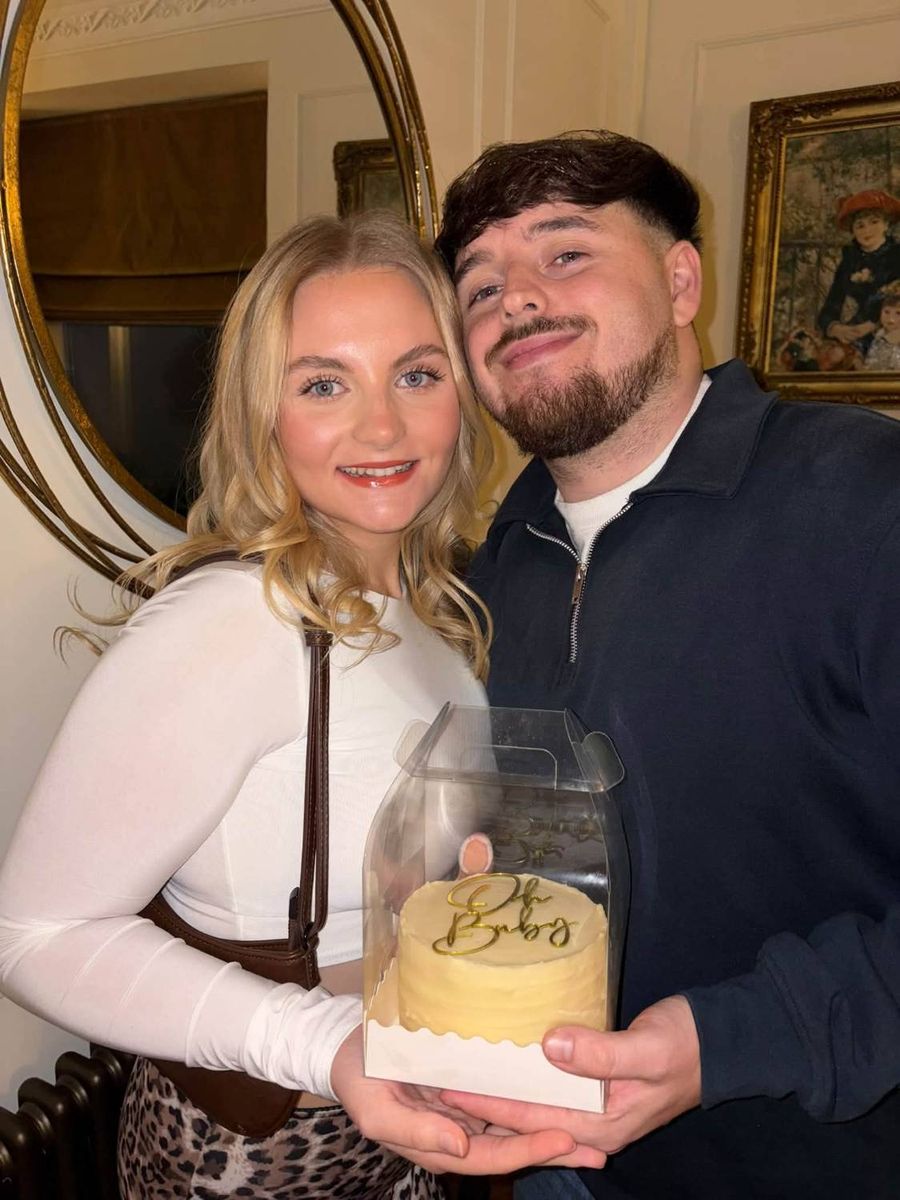 Lucy and partner smiling, holding an Oh Baby cake